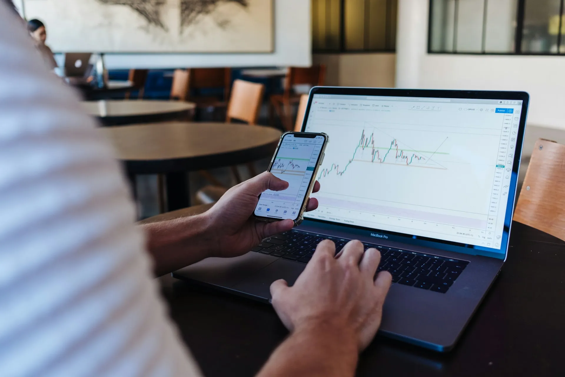 An image of a man in front of a computer that is showing a candle chart.